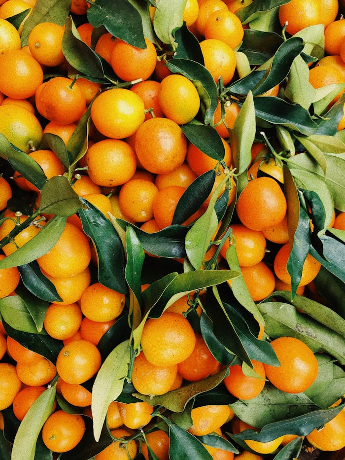 about-us A vibrant pile of fresh tangerines with green leaves, showcasing natural freshness and vivid colors.